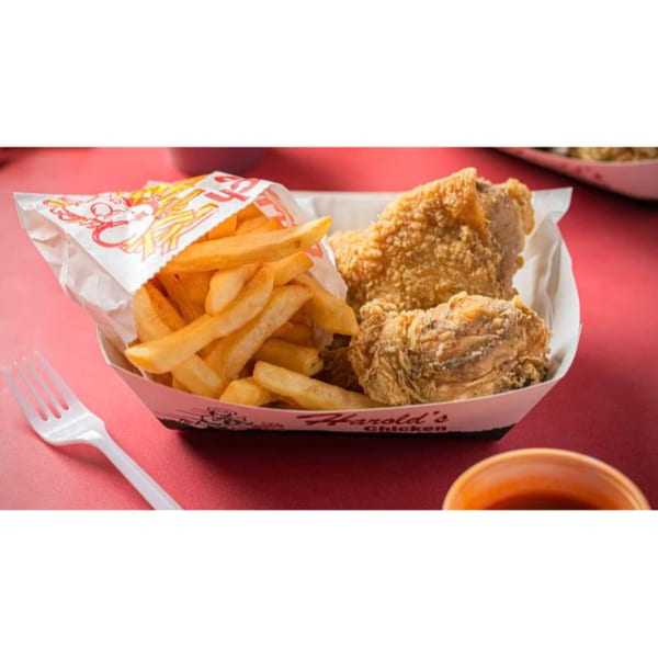 Harold's Chicken Shack fried chicken and fries in a paper boat on a red table.