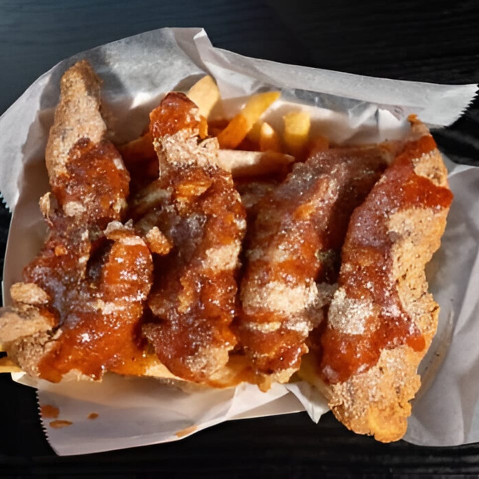 Harold's Chicken Shack #30 fried chicken tenders with sauce and fries in a paper-lined basket.